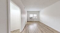 Located at 1310 S Wilton Place in Los Angeles, CA, this efficient one-bedroom, one-bathroom unit offers a thoughtfully designed layout across a single floor. The main living area features light wood-look flooring, crisp white walls, and a textured ceiling, creating a clean and bright atmosphere. A window unit provides climate control, while a large window with blinds allows natural light to fill the room. The kitchen is outfitted with white shaker-style cabinetry, dark granite countertops, a stainless steel sink, and a full-size stainless steel refrigerator, along with a gas range, offering a functional and modern cooking space. The spacious primary bedroom includes a mirrored sliding closet door and continues the consistent wood-look flooring found throughout the unit, providing a calm and neutral retreat. The bathroom is a standout feature, showcasing large-format marble-look tile surrounding the soaking tub and shower, complemented by matte black fixtures and hardware, a white vanity, and a mirrored medicine cabinet. Two closets provide practical storage solutions. The unit's clean, updated finishes and efficient use of space make it a well-appointed option in the Mid-City Los Angeles area.