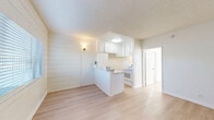 Located at 835 W Rosecrans Ave in Los Angeles, CA, this efficient single-story, 1-bedroom, 2-bathroom unit is thoughtfully designed to maximize every inch of its compact footprint. Light wood laminate flooring runs throughout, lending a clean and cohesive aesthetic across all rooms.

The combined dining and living area is open and airy, benefiting from natural light that filters through horizontal blinds and casts warm, patterned shadows across the floor. A charming shiplap accent wall adds a touch of texture and character to the living space.

The kitchen is open to the main living area and features a peninsula-style breakfast bar with a marble-look countertop, white cabinetry, and a white range — all contributing to the home's crisp, bright palette. A dedicated pantry provides valuable additional storage.

The bedroom is generously proportioned relative to the overall unit and is bathed in natural light from a window. It includes a closet with sliding panel doors, offering practical storage solutions. The textured ceiling carries throughout the space, adding a subtle design layer.

Both bathrooms are finished in clean white tile, with one featuring a full soaking tub and shower combo with chrome fixtures and a window above for natural ventilation. The overall ambiance of the unit is light, minimal, and move-in ready.