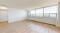 Located on the 8th floor at 3390 Keele Street in Toronto's north end, this one-bedroom, one-bathroom unit offers a well-designed layout with consistent light wood laminate flooring and crisp white walls throughout. The open-concept living and kitchen area makes efficient use of the space, with large floor-to-ceiling windows along the exterior wall flooding the room with natural light and framing expansive views of the surrounding cityscape and greenery. Baseboard heating units run beneath the windows, and the textured white ceiling adds a subtle architectural detail.

The kitchen is thoughtfully appointed with white shaker-style cabinetry extending to the ceiling for ample storage, a classic white subway tile backsplash, stainless steel appliances including a full-size French door refrigerator and dishwasher, a dark countertop island, and track lighting overhead.

The bedroom is a comfortable, well-proportioned room featuring the same light wood flooring, a large window with sweeping outdoor views, and a double-door closet providing generous storage.

The bathroom is finished with floor-to-ceiling white subway tile in the tub/shower surround, a sleek white vanity with an undermount sink, chrome fixtures, and a large mirror, creating a clean and bright aesthetic throughout.