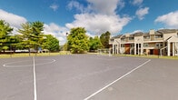 Located at 1820 Hickory Creek Ln in Columbus, Ohio, this expansive outdoor recreational court offers a generously sized, single-level paved surface designed to accommodate multiple sports and activities. The court features clearly marked playing lines and includes a full-size soccer goal, making it well-suited for organized matches as well as casual play. The smooth asphalt surface provides a durable, all-weather foundation ideal for a variety of athletic pursuits.

The surrounding environment enhances the space considerably. Mature deciduous trees frame the perimeter, providing natural shade and a park-like ambiance that softens the open expanse of the court. A tall light pole is positioned nearby, suggesting the facility supports use during evening hours as well. A perimeter fence defines the boundary of the space, offering a sense of enclosure without obstructing sightlines to the lush green landscape beyond.

The court sits adjacent to a multi-story residential building, integrating seamlessly into the broader community setting. Open skies above and the verdant tree line create an inviting outdoor atmosphere, making this a functional and appealing recreational amenity. The overall scale of the court comfortably accommodates multiple players simultaneously, reflecting its design as a shared community sport and recreation facility.
