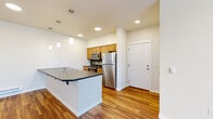 Located at 4245 E Poleline Ave in Post Falls, Idaho, this single-floor residence offers a clean, functional layout with quality finishes throughout. The open-concept kitchen and living area serves as the heart of the home, featuring warm hardwood-style flooring, recessed lighting, and stylish pendant lights overhead. The kitchen is well-appointed with stainless steel appliances including a refrigerator, range, and microwave, complemented by honey-toned wood cabinetry, a dark countertop, a tile backsplash, and a peninsula with an integrated sink that provides additional prep space and casual seating. The living area is bright and open with neutral walls that maximize the sense of space. The bedroom is carpeted for comfort and includes a closet with built-in shelving. The bathroom features a wood-toned vanity with ample storage, a large mirror with vanity lighting, and a full tub-shower combination. A baseboard heating system ensures year-round comfort. The entry door opens directly into the main living space, creating a seamless flow. Clean white walls, consistent flooring materials, and thoughtful finishes give this residence a cohesive, move-in-ready appearance throughout.