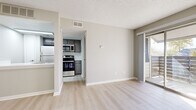 This single-floor unit offers a clean, modern aesthetic with a neutral color palette throughout. The open living area features light wood-style luxury vinyl flooring that extends seamlessly through the main spaces, complemented by a textured ceiling and crisp white baseboards. A sliding glass door floods the living room with natural light and provides direct access to a private balcony, offering a pleasant outdoor retreat.

The kitchen is efficiently designed and outfitted with stainless steel appliances, including a refrigerator, electric range, and over-the-range microwave. Gray cabinetry and a subway tile backsplash add a contemporary touch, while light flooring ties the kitchen visually to the rest of the main living area.

The bedroom is carpeted for comfort and features a window with blinds that allows natural light to filter in. A mirrored sliding closet provides generous storage, and the room connects conveniently to a dedicated bathroom. The bathroom is finished with large-format gray tile surrounding a full soaking tub and shower combination, fitted with chrome fixtures for a polished look.

Throughout the unit, neutral gray walls create a versatile and inviting backdrop, making the space move-in ready and easy to personalize.