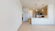This single-floor residence showcases a clean, contemporary design throughout. The open-concept kitchen serves as a central highlight, equipped with a full suite of stainless steel appliances including a refrigerator, range, and over-the-range microwave. Taupe shaker-style cabinetry provides generous storage, complemented by a tiled backsplash and a central island with a light-toned countertop and pendant lighting overhead — ideal for both meal preparation and casual dining.

Light wood-style flooring extends seamlessly throughout the unit, creating a cohesive and airy aesthetic. The bedroom features two windows fitted with blinds, allowing ample natural light and outdoor views, and is equipped with a ceiling fan for added comfort. A closet is accessible directly from the bedroom, and additional doors connect to the surrounding hallway layout.

The bathroom is well-appointed, offering a soaking tub with a tiled surround in neutral tones, brushed nickel fixtures, and a clean, minimal design. Consistent white walls and recessed lighting throughout the unit contribute to a bright, move-in ready atmosphere. The overall layout is efficient and thoughtfully organized, offering a comfortable, modern living environment.
