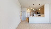 This single-floor residence showcases a clean, contemporary design throughout. The open-concept kitchen serves as a central highlight, equipped with a full suite of stainless steel appliances including a refrigerator, range, and over-the-range microwave. Taupe shaker-style cabinetry provides generous storage, complemented by a tiled backsplash and a central island with a light-toned countertop and pendant lighting overhead — ideal for both meal preparation and casual dining.

Light wood-style flooring extends seamlessly throughout the unit, creating a cohesive and airy aesthetic. The bedroom features two windows fitted with blinds, allowing ample natural light and outdoor views, and is equipped with a ceiling fan for added comfort. A closet is accessible directly from the bedroom, and additional doors connect to the surrounding hallway layout.

The bathroom is well-appointed, offering a soaking tub with a tiled surround in neutral tones, brushed nickel fixtures, and a clean, minimal design. Consistent white walls and recessed lighting throughout the unit contribute to a bright, move-in ready atmosphere. The overall layout is efficient and thoughtfully organized, offering a comfortable, modern living environment.