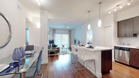 This well-appointed single-floor residence offers a thoughtfully designed open-concept layout that seamlessly connects the kitchen, dining, and living areas. Rich hardwood flooring flows throughout the main living spaces, anchoring the contemporary aesthetic established by crisp white walls and modern fixtures.

The kitchen is outfitted with dark espresso cabinetry, stainless steel appliances including a refrigerator, range, microwave, and dishwasher, and a white quartz peninsula with bar seating illuminated by sleek pendant lighting. Adjacent to the kitchen, the dining area accommodates a full glass-top table and is accented by a decorative round mirror, while a dedicated workspace adds functional versatility.

The living room is bright and welcoming, featuring a large sliding glass door with vertical blinds that fills the space with natural light and provides outdoor access. A ceiling fan overhead and ample wall space for artwork complete this comfortable gathering area.

Both bedrooms are generously sized, each featuring hardwood floors, ceiling fans, and walk-in closets. The primary bedroom includes additional built-in shelving for storage. The bathrooms feature tile flooring, dark wood vanities with granite countertops, and a shower-tub combination. The unit's overall design balances modern style with practical functionality throughout.