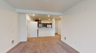 This single-floor unit offers a well-organized layout designed for comfortable everyday living. The open-concept living area is finished with neutral-toned carpet and crisp white walls, creating a clean and versatile backdrop. Large windows allow natural light to fill the space while providing views of the surrounding exterior.

The kitchen is positioned at the heart of the unit, defined by a peninsula with marble-style countertops that doubles as a casual bar or workspace. Dark espresso cabinetry provides ample storage, and the kitchen is equipped with stainless steel appliances including a refrigerator, microwave, and range. Recessed lighting overhead adds functional illumination throughout the cooking area.

The bedrooms continue the soft carpet flooring and neutral palette, with windows that bring in natural light. One bedroom features a large window with vertical blinds and views of neighboring structures. The bathrooms are finished with wood-look tile flooring, dark vanity cabinetry, marble-style countertops, full-width mirrors, and a tub-shower combination, lending a polished, cohesive aesthetic. A wall-mounted HVAC unit and a private exterior door add practical utility to the living space.