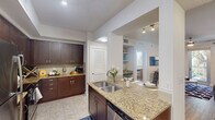 Located at 250 Congress Park Dr in Delray Beach, Florida, this single-story 2-bedroom, 2-bathroom residence offers a thoughtfully designed layout that balances comfort and functionality. The open-concept kitchen is a standout feature, showcasing rich dark wood cabinetry, granite countertops, a double-basin sink, tile flooring, and a full suite of stainless steel appliances. A breakfast bar with seating connects the kitchen to the living area, making it ideal for everyday dining and entertaining.

The living room is bright and welcoming, with wood-style flooring, a ceiling fan, and large windows and a glass door that invite natural light and offer views of lush tropical palm trees outside. The spacious primary bedroom includes its own ceiling fan, wood-style floors, a walk-in closet with built-in shelving, and a private en-suite bathroom. The primary bath features a glass-enclosed shower, granite vanity, dark wood cabinetry, and tile floors. The second bedroom is equally well-lit with tropical garden views.

Both closets offer generous storage with wire shelving systems. An in-unit laundry area includes a full-size washer and dryer. The clean, neutral color palette throughout creates a bright and airy atmosphere that reflects the relaxed Florida lifestyle.