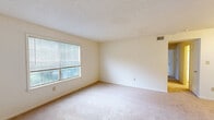 Located at 1525 Twin Oaks Ln in Virginia Beach, Virginia, this single-floor, 2-bedroom, 2-bathroom home offers a practical and well-organized layout. The combined living and dining area serves as the heart of the home, featuring neutral carpet flooring, cream-toned walls, and a textured ceiling. A front entry door with classic panel detailing and brass hardware opens into this bright, open space. The kitchen is conveniently positioned nearby, complementing the flow of the common areas. A hallway connects the main living spaces to the private quarters. The primary bedroom is a generously sized retreat, complete with carpet flooring, natural light from a large window with blinds, and direct access to its own bathroom. It also features a mirrored sliding-door closet, adding both storage and a sense of openness. The second bedroom is similarly appointed, with carpet flooring, neutral walls, and a window that brings in natural light. Both bathrooms are functional and clean, one featuring a shower stall and the other a full tub-shower combo with tiled surround and standard fixtures. Throughout the home, the consistent use of light, neutral tones creates a cohesive and move-in ready atmosphere.