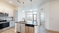 Located at 1900 Olevia St in Jacksonville, Florida, this well-appointed one-bedroom, one-bathroom unit offers a thoughtfully designed layout with modern finishes throughout. The open-concept kitchen and dining area serves as the heart of the space, featuring a large center island with a dark granite countertop, white upper cabinetry, gray lower cabinetry, a subway tile backsplash, and a full suite of stainless steel appliances. Stylish geometric pendant lights hang above the island, adding a contemporary touch. Light wood-look flooring runs throughout the main living areas, enhancing the bright, clean aesthetic.

The bedroom is generously sized and carpeted for comfort, benefiting from large windows that allow ample natural light and offer outdoor views. A ceiling fan adds functionality, and the room connects directly to a spacious walk-in closet outfitted with multi-level wire shelving for organized storage.

The bathroom is elegantly finished with wood-look flooring, gray cabinetry, granite countertops, a framed mirror, and matte black fixtures. The tub-shower combination features full white subway tile surround, completing the cohesive, modern design. Clean white walls and recessed lighting throughout contribute to an overall bright and inviting atmosphere.