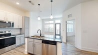 Located at 1900 Olevia St in Jacksonville, Florida, this well-appointed one-bedroom, one-bathroom unit offers a thoughtfully designed layout with modern finishes throughout. The open-concept kitchen and dining area serves as the heart of the space, featuring a large center island with a dark granite countertop, white upper cabinetry, gray lower cabinetry, a subway tile backsplash, and a full suite of stainless steel appliances. Stylish geometric pendant lights hang above the island, adding a contemporary touch. Light wood-look flooring runs throughout the main living areas, enhancing the bright, clean aesthetic.

The bedroom is generously sized and carpeted for comfort, benefiting from large windows that allow ample natural light and offer outdoor views. A ceiling fan adds functionality, and the room connects directly to a spacious walk-in closet outfitted with multi-level wire shelving for organized storage.

The bathroom is elegantly finished with wood-look flooring, gray cabinetry, granite countertops, a framed mirror, and matte black fixtures. The tub-shower combination features full white subway tile surround, completing the cohesive, modern design. Clean white walls and recessed lighting throughout contribute to an overall bright and inviting atmosphere.