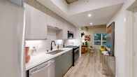 Located at 800 N Front St in Burbank, CA, this thoughtfully designed studio offers a modern living experience within a compact, efficiently organized floor plan. Light wood-style flooring flows throughout, complementing the clean, contemporary aesthetic.

The kitchen is a standout feature, showcasing two-tone cabinetry with sage green lower cabinets and light wood upper cabinets, white quartz countertops, a subway tile backsplash, and a full suite of stainless steel appliances including a gas range, dishwasher, refrigerator, and microwave. The galley-style layout maximizes functionality and storage.

The living and sleeping area benefits from soaring exposed concrete ceilings that lend an industrial-chic character to the space. A large window frames lush greenery outside, filling the room with natural light and a sense of connection to the outdoors.

The bathroom is finished with large-format gray tile on both the floors and shower surround, complemented by a green vanity with a white countertop and a full soaking tub. Built-in shelving adds practical storage.

Additional conveniences include an in-unit laundry area and a dedicated closet. The overall ambiance is modern and stylish, blending industrial elements with warm, inviting finishes throughout.