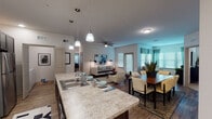 This single-floor residence offers a thoughtfully designed open-concept layout that seamlessly connects the kitchen, dining, and living areas. The kitchen is a standout feature, boasting dark espresso cabinetry, granite-style countertops, stainless steel appliances including a range, microwave, and refrigerator, and a large central island with pendant lighting overhead — ideal for both meal prep and casual dining. Wood-look flooring runs throughout the main living areas, adding warmth and continuity to the space. The dining area comfortably accommodates a full-sized table and sits adjacent to the kitchen, while the living room features ceiling fans and multiple windows that invite generous natural light. A dedicated sitting room or den provides additional flexible living space, lined with large windows dressed in decorative curtains. Both bedrooms are carpeted and equipped with ceiling fans, offering a comfortable retreat. Each connects to its own bathroom; the primary bath features dark cabinetry with dual sinks and granite-style countertops, while the secondary bath mirrors the same refined finishes. A conveniently located in-unit laundry area with full-sized washer and dryer completes this well-rounded, move-in-ready home.