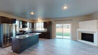 This well-appointed 2-bedroom, 2-bathroom single-floor residence in Kimberly, Wisconsin offers a thoughtfully designed layout with modern finishes throughout. The open-concept kitchen serves as the heart of the home, showcasing rich dark cabinetry, granite countertops, stainless steel appliances including a range, microwave, and refrigerator, and a central island with an integrated sink. Multiple windows flood the kitchen with natural light and provide pleasant outdoor views, while a sliding glass door connects the living area directly to the exterior. Light-toned luxury vinyl plank flooring runs throughout the main living areas, creating a clean and cohesive aesthetic. The bedrooms are generously sized, each featuring ceiling fans, large windows, and baseboard heating. The primary suite includes a walk-in closet outfitted with wire shelving systems for ample storage, as well as a private en-suite bathroom with a walk-in shower and granite-topped vanity. The second bathroom features a full tub-shower combination and a matching dark-stained vanity with granite countertop. A wall-mounted mini-split unit in the living area provides additional climate control comfort. The overall ambiance is clean, modern, and move-in ready.