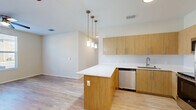Located at 800 Everett Way in Perry, FL, this single-story, 3-bedroom, 2-bathroom home offers a clean, modern design with consistent light wood-style flooring throughout. The open-concept living area seamlessly connects the kitchen, dining, and living spaces, creating a bright and functional layout. The kitchen is well-appointed with warm wood-toned cabinetry, white quartz countertops, stainless steel appliances including a refrigerator, range, microwave, and dishwasher, and a peninsula island with pendant lighting overhead — ideal for both meal prep and casual dining. The living and dining area is illuminated by a ceiling fan with light and a window offering views of the surrounding neighborhood. Each of the three bedrooms features light-filled windows, ceiling fans, and neutral wall tones. The primary bedroom is a comfortable size with its own dedicated closet space. Four closets in total provide ample storage throughout the home. The two bathrooms are finished with wood-toned vanities, white countertops, and walk-in showers with chrome fixtures. A dedicated laundry area and a connecting hallway complete the practical and well-organized floor plan of this move-in-ready home.