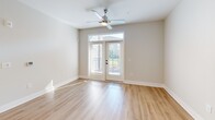 Located at 7100 Summerside Dr in Whitsett, NC, this well-appointed one-bedroom, one-bathroom unit offers a thoughtfully designed single-floor layout with a clean, modern aesthetic. Light hardwood-style flooring runs throughout, complementing the neutral gray and white color palette that gives the space a bright, cohesive feel.

The open-concept kitchen and living area serves as the heart of the unit. The kitchen is equipped with gray shaker-style cabinetry, granite countertops, a subway tile backsplash, stainless steel appliances including a range, microwave, and refrigerator, and a center island with a sink and pendant lighting above. The adjacent living area features a ceiling fan and glass-paned double doors with transom windows that invite natural light and offer outdoor views.

The bedroom is a comfortable, well-proportioned room with a ceiling fan, a window with exterior views, and access to a closet. The bathroom features a large walk-in shower with frameless sliding glass doors, built-in shelving, and gray cabinetry above the toilet for additional storage. A dedicated laundry room with a full-size washer and dryer and overhead shelving adds everyday convenience. The unit combines functional design with modern finishes throughout.