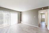 Located at 5800 Maplebrook Ln in Grand Blanc, MI, this two-bedroom, one-bathroom single-floor unit offers a clean, modern aesthetic throughout. Light wood-style flooring flows seamlessly from room to room, complemented by neutral gray and taupe wall tones that create a bright, cohesive atmosphere.

The living room is a welcoming space anchored by large sliding glass doors fitted with vertical blinds, allowing abundant natural light to fill the room. The galley-style kitchen is well-appointed with crisp white shaker cabinetry, a gray tile backsplash, light quartz-style countertops, a single-basin sink with a matte black faucet, and a full suite of stainless steel appliances including a range, microwave, and refrigerator.

Both bedrooms feature light wood flooring, neutral walls, and windows with horizontal blinds that provide natural light and privacy. Each bedroom includes a dedicated closet with sliding six-panel doors and built-in shelving, offering practical storage. The primary bedroom is generously proportioned with ample room for furnishings.

The full bathroom is outfitted with a tub-shower combination, chrome fixtures, and light wood-style flooring. A hallway connects the bedrooms and bathroom, keeping the layout functional and efficient. Two additional closets provide further storage throughout the unit.