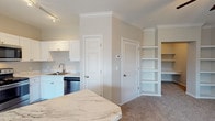 Located in Rockport, TX, this single-floor residence offers a well-designed layout with a clean, contemporary aesthetic throughout. The open-concept kitchen is a standout feature, showcasing white shaker cabinetry, striking marble-style countertops, and a full suite of stainless steel appliances including a refrigerator, gas range, microwave, and dishwasher. A central kitchen island provides additional prep space and serves as a natural divider between the kitchen and the carpeted living area, which is brightened by multiple windows dressed with white blinds and finished with a ceiling fan overhead. Crown molding adds a refined architectural detail throughout the main living spaces. Built-in shelving units offer practical storage and display options adjacent to the living area. The bathroom is thoughtfully appointed with dark hardwood-style flooring, a full soaking tub with shower, a dual-sink vanity with white cabinetry and marble-style countertops, and ample counter space. Bedrooms are carpeted and feature ceiling fans, natural light from windows, and generous closet space, including a walk-in closet outfitted with double wire shelving rods. The overall ambiance is bright, neutral, and move-in ready, with consistent finishes that create a cohesive and comfortable living environment.