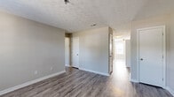 This single-floor residence offers a practical and efficient layout across two bedrooms and two bathrooms. The interior is finished with durable wood-look plank flooring throughout the main living areas and kitchen, transitioning to plush carpet in both bedrooms. Textured ceilings with a decorative patterned finish add visual interest throughout the unit.

The kitchen is equipped with gray shaker-style cabinetry, light stone countertops, and black appliances including an electric range, dishwasher, and refrigerator. A window above the sink area brings in natural light, and the space opens toward the main living area for a connected feel.

The living room is a well-proportioned open space with neutral gray-toned walls and clean white trim. A hallway connects the main areas to both bedrooms and bathrooms, providing a logical and private flow. The primary bedroom is a generously sized room with wood-look flooring, while the secondary bedroom features carpet and a window that allows natural light to filter in. Both bedrooms maintain the same neutral color palette and patterned ceilings.

The bathrooms include a full tub-shower combo with clean white surrounds and chrome fixtures. A closet provides additional dedicated storage. The overall ambiance is clean, neutral, and move-in ready.