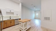 This thoughtfully designed 1-bedroom, 1-bathroom unit delivers a clean, modern aesthetic across a single floor. The open-concept layout connects the kitchen and living area seamlessly, creating an airy and functional living environment. Light wood-tone luxury vinyl plank flooring runs throughout the main living spaces, complementing the crisp white walls and abundant recessed lighting overhead.

The kitchen is a standout feature, showcasing white shaker-style upper cabinets paired with warm wood lower cabinetry, granite countertops, and a full suite of stainless steel appliances including a refrigerator, range, microwave, and dishwasher. A freestanding butcher block island adds additional prep space and visual warmth to the room. Tall ceilings lend a sense of openness throughout the main living area, which also features a ceiling fan and a window that invites natural light.

The bedroom is a calm, carpeted retreat with neutral tones and a window with blinds offering outside views. The bathroom is well-appointed with a wood-toned vanity, granite countertop, undermount sink, matte black fixtures, and an illuminated mirror. A dedicated closet provides convenient storage. This unit offers a well-balanced, modern living experience with quality finishes at every turn.