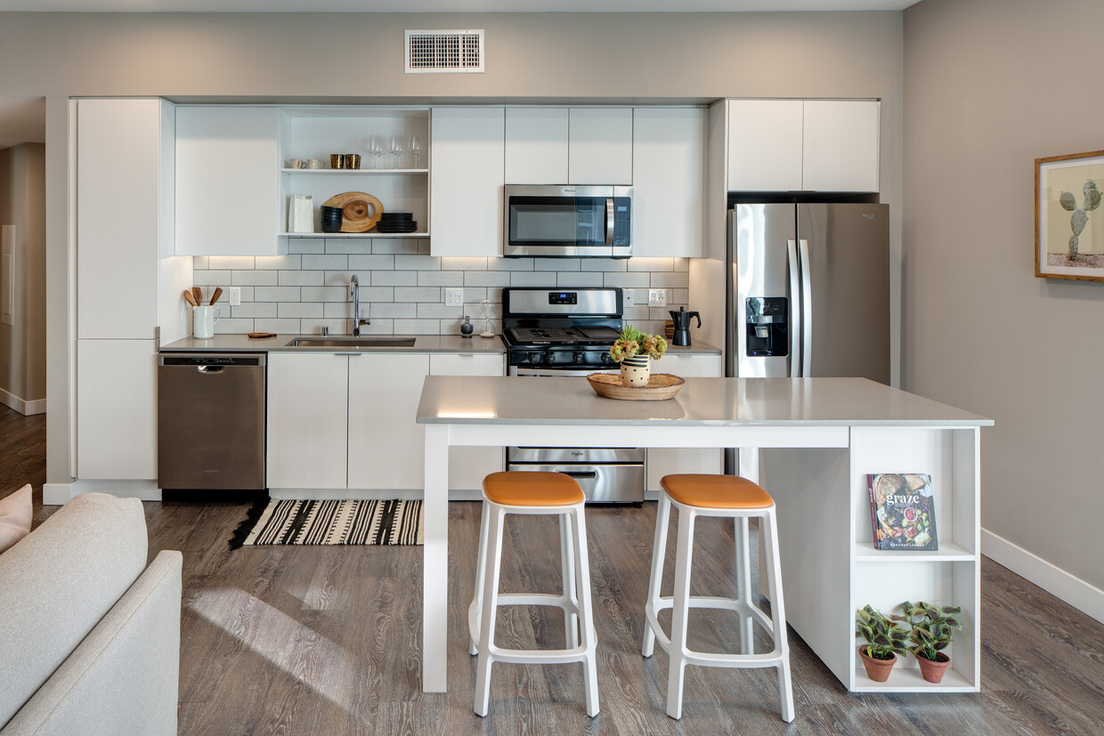 Open concept kitchen with quartz countertops, island, tile backsplash, and stainless steel appliances - AVA Hollywood at La Pietra Place