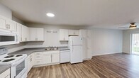 Located at 907 Ikes Peak Rd in Clinton, Iowa, this well-appointed 2-bedroom, 1-bathroom single-story residence offers a thoughtfully designed layout with modern finishes throughout. The open kitchen and living area form the heart of the home, featuring white shaker-style cabinetry, granite-look countertops, a double sink, and a full suite of white appliances including a refrigerator, dishwasher, electric range, and microwave. Wood-look plank flooring runs through the main living areas, adding warmth and visual continuity. The spacious living room benefits from natural light through a large sliding glass door fitted with vertical blinds, and is finished with a ceiling fan overhead. Two bedrooms provide comfortable accommodations — the primary bedroom is generously sized with its own ceiling fan, while the secondary bedroom also features a sliding glass door for added natural light. One bedroom features plush carpeting for added comfort. The full bathroom is accessibility-friendly, equipped with grab bars, a vanity with white cabinetry, and matching hard-surface flooring. A dedicated laundry room houses a full-size top-load washer and dryer. Two closets provide ample storage throughout the residence.