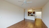 This single-floor residence offers a thoughtfully designed open-concept layout that connects the living area and kitchen seamlessly. The generously sized living room features warm wood-look flooring, a ceiling fan, and a large window that allows natural light to fill the space, creating a bright and welcoming atmosphere.

The kitchen is well-equipped with dark espresso cabinetry, granite-style countertops, and a full suite of stainless steel appliances, including an electric range, microwave, and refrigerator. Pendant lighting above the breakfast bar adds a stylish touch, while the open pass-through design keeps the kitchen connected to the main living area.

The bedroom is carpeted for comfort, features its own ceiling fan, and includes a large window for natural light. A spacious walk-in closet with wire shelving on multiple walls provides extensive storage and organization options.

The bathroom is clean and functional, offering a full soaking tub and shower combination with tile surround, granite-style vanity countertop, and wood-look tile flooring. A louvered closet door near the kitchen corridor adds a classic design detail to the hallway connecting the living and private areas of the residence.