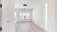 This thoughtfully designed 2-bedroom, 1-bathroom residence offers a clean, contemporary aesthetic throughout its single-floor layout. The open-concept kitchen and living area serves as the heart of the home, highlighted by striking navy blue cabinetry, a white quartz waterfall island with an integrated sink, a subway tile backsplash, and a full suite of stainless steel appliances including a gas range and French door refrigerator. A large sliding glass door connects the kitchen directly to a private balcony, filling the space with abundant natural light and offering open urban views.

Light-toned hardwood flooring runs throughout the main living areas, complementing the bright white walls and recessed lighting. The primary bedroom is a well-proportioned retreat featuring light hardwood floors, a large window with urban views, and a dedicated closet. The second bedroom is finished with plush neutral carpet and a ceiling fan, offering a comfortable and quiet space. Both bedrooms benefit from generous natural light through sizable windows fitted with blinds.

The bathroom is finished with warm wood-tone flooring, crisp white walls, a full tub/shower combination, and matte black hardware and fixtures, adding a modern, contrasting detail. The overall design is cohesive, minimal, and move-in ready.