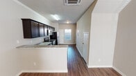 Located on SE 16th St in Mineral Wells, Texas, this two-story residence offers a thoughtfully designed interior with modern finishes throughout. The open-concept kitchen is a standout feature, equipped with stainless steel appliances including a refrigerator, electric range, and built-in microwave. Rich dark cabinetry extends to the ceiling for ample storage, complemented by granite-style countertops and a double-basin sink. The kitchen flows seamlessly into the main living area, which features warm hardwood-style flooring, crown molding, and a ceiling fan — with natural light entering through a front-facing window. Bedrooms are carpeted for comfort, each featuring ceiling fans with light fixtures and windows that bring in natural light. The bathroom includes a granite-topped vanity, hardwood-style flooring, and brushed nickel hardware accents. An additional area on the upper level showcases angled architectural detailing, adding visual interest to the space. Throughout the residence, neutral warm-toned walls provide a versatile backdrop, while consistent trim work and hardwood-style flooring on the main level create a cohesive aesthetic. The layout is functional and well-suited for everyday living.