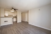 This well-designed one-bedroom, one-bathroom unit makes smart use of its compact footprint across a single floor. Consistent hardwood-style flooring flows throughout the entire space, lending a cohesive and clean aesthetic from room to room. The open-concept living and kitchen area forms the heart of the unit. The living area is bathed in natural light from a large sliding glass door that opens to a private patio, offering outdoor views and easy access to fresh air. A ceiling fan overhead adds both function and a touch of warmth to the space. The kitchen is thoughtfully appointed with white cabinetry, speckled laminate countertops, a stainless steel refrigerator, a dishwasher, and a built-in breakfast bar that connects the cooking and living areas. The bedroom is a comfortable, well-proportioned room with natural light provided by a window with vertical blinds. It connects conveniently to the hallway, which also provides access to the full bathroom. The bathroom features a combined tub and shower, a toilet, and a vanity with a large mirror and dark-toned countertop. Neutral warm-beige walls throughout the unit create a calm, versatile backdrop suitable for a variety of décor styles.