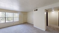 Located at 5300 Eubank Blvd NE in Albuquerque, New Mexico, this single-floor residence features two bedrooms and two bathrooms within a functional and efficient layout. The home's warm, neutral color palette and cream-toned walls create a cohesive atmosphere throughout.

The galley-style kitchen is well-appointed with rich wood cabinetry, ample upper and lower storage, a double-basin sink with laminate countertops, and white appliances including a refrigerator and range. Wood-look flooring adds a clean, durable finish to the space. A ceiling fan with integrated lighting serves the area adjacent to the kitchen, which benefits from natural light through a window with vertical blinds.

The spacious primary bedroom features plush carpeting, a large window that invites natural light, and a textured ceiling. The second bedroom is similarly carpeted and bright, with its own window and direct access to a closet. Both bathrooms are clean and functional, with one featuring a full tub-and-shower combo, wood-finish flooring, and warm wood cabinetry for storage.

A hallway with wood-look flooring connects the rooms, and multiple ceiling vents throughout ensure consistent climate control. The overall design is practical and comfortable, making efficient use of the available space.