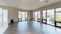 This well-appointed 3-bedroom, 2-bathroom single-floor residence offers a thoughtfully designed layout with a seamless blend of modern finishes and functional living spaces. The open-concept living and dining area features wood-look flooring and a ceiling fan, while expansive floor-to-ceiling windows flood the space with natural light and provide views of the surrounding streetscape. The kitchen is a standout, showcasing dark espresso cabinetry that reaches to the ceiling, stainless steel appliances including a refrigerator, range, and microwave, a classic white subway tile backsplash, and a large island with light quartz countertops and pendant lighting overhead. The bedrooms are carpeted for comfort, each equipped with ceiling fans; one bedroom features a sliding glass door providing direct outdoor access, while another includes a dedicated walk-in closet with multi-tiered shelving for ample storage. Both bathrooms are clean and functional, featuring tub-shower combinations, wood-look flooring, and dark vanity cabinetry with light countertops. The overall ambiance of the residence is modern and neutral, with consistent design choices throughout that create a cohesive and move-in-ready living environment.
