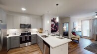 This single-story residence in Cypress, Texas offers a well-designed open-concept layout that maximizes functionality and style. The kitchen serves as a central highlight, featuring gray shaker-style cabinetry, white quartz countertops, a large peninsula with bar seating, and a full suite of stainless steel appliances including a refrigerator with ice maker, electric range, over-the-range microwave, and dishwasher. Under-cabinet lighting and pendant lights above the peninsula add warmth and practicality to the space. Wood-style plank flooring flows throughout the main living areas, creating a cohesive and modern aesthetic.

The living area is comfortably proportioned, featuring large windows that allow ample natural light and a ceiling fan overhead. A sliding glass door provides access to the exterior. The bedroom is a well-sized retreat with its own large window, ceiling fan, and direct access to the full bathroom. The bathroom includes a soaking tub with shower combination, a gray vanity with white countertop, and a framed mirror. A walk-in closet adjacent to the bathroom provides organized storage space. Crisp white walls and clean architectural lines throughout give the residence a bright, contemporary feel.