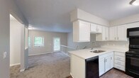 Located at 200 Lake Forest Blvd in Kalamazoo, MI, this two-story, two-bedroom, two-bathroom residence offers a well-organized layout spread across two floors. The main level features an open-concept kitchen and living room combination, where the kitchen stands out with crisp white shaker cabinetry, white quartz countertops, a peninsula with a stainless steel sink, black appliances including a range, built-in microwave, and refrigerator, and durable hardwood-style flooring. A charming built-in bench nook near the window adds a functional design touch. The living area flows naturally from the kitchen, anchored by a classic corner fireplace with a white mantel and surrounded by large windows that invite ample natural light and views of the greenery outside. Soft carpeting adds warmth throughout the living spaces. The upper level hosts both bedrooms, each carpeted and well-lit by wide windows, including a generously sized primary bedroom. Two full bathrooms serve the home — one features hexagonal tile flooring, a white vanity with quartz countertops, and a tub-shower combination, while the second offers wood-look tile flooring and a similarly appointed tub-shower setup. A staircase and hallway connect the two levels seamlessly, completing this functional and inviting home.