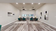 Located at 3805 McCain Park Dr in North Little Rock, AR, this single-story community space is thoughtfully designed with a modern aesthetic and functional layout throughout. The leasing area features soaring vaulted ceilings, two large ceiling fans, recessed lighting, and dual workstations with dark wood desks and teal upholstered chairs, all set atop light wood-look flooring. A welcoming lounge area adjoins the main space, offering stylish mid-century modern seating, decorative wall accents, and natural light from large windows with clean white blinds. The open lounge and social area is generously sized, accommodating high-top bar seating along windowed walls, a comfortable sectional seating arrangement, a wall-mounted TV, and ceiling fan — creating an inviting environment for residents to gather. A well-appointed kitchen features white shaker cabinetry, quartz countertops, stainless steel appliances including a refrigerator, range, and dishwasher, along with a matte black sink fixture and a stylish geometric backsplash accent wall. A dedicated fitness center rounds out the amenities, offering a spacious open floor plan with polished concrete floors, mirrored walls, a wall-mounted TV, natural light from multiple windows, and a full array of cardio and strength equipment.