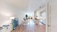 This contemporary single-floor residence showcases a clean, modern aesthetic throughout, characterized by crisp white walls, light wood flooring, and an abundance of natural light. The open-concept layout seamlessly connects the kitchen, dining, and living areas, creating a cohesive and airy atmosphere.

The kitchen is outfitted with sleek grey cabinetry, white quartz countertops, a white subway tile backsplash, and a full suite of stainless steel appliances including a refrigerator, range, microwave, and dishwasher. A butcher block-topped island provides additional prep space and casual seating, flowing naturally into the dining area.

The living room benefits from large windows that frame outdoor greenery, filling the space with natural light and creating a warm, inviting ambiance. The bedroom continues the bright, serene palette, featuring a generous window with outdoor views and warm wood flooring.

Two bathrooms serve the residence. The primary bathroom offers a double-sink vanity with white quartz countertops, a large mirror, and a glass-enclosed shower. The secondary bathroom is efficiently designed with a glass-door shower stall, a single vanity, and neutral tile flooring. Together, the spaces reflect a cohesive modern design with thoughtful finishes throughout.