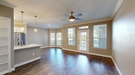 This thoughtfully designed 1-bedroom, 2-bathroom residence offers an efficient and comfortable single-floor layout finished with rich, dark hardwood-style flooring that flows consistently throughout the space. The living room serves as the welcoming centerpiece, highlighted by a charming bay window that floods the room with natural light and offers outdoor views, complemented by crown molding, a ceiling fan, and a private entry door with transom window above.

The open-concept kitchen is a functional standout, featuring white shaker cabinetry, a decorative arabesque tile backsplash, a center island with an integrated sink, stainless steel appliances including a range, microwave, dishwasher, and refrigerator, and elegant pendant lighting overhead.

The spacious primary bedroom continues the hardwood-style flooring, includes crown molding, a ceiling fan, and a window for natural light. It connects directly to a dedicated walk-in closet outfitted with wire shelving and multi-tier storage racks for well-organized storage. Two full bathrooms provide practical convenience, each finished with neutral tones, white vanities, and hardwood-style flooring. Throughout the residence, crown molding and neutral warm-toned walls lend a clean, cohesive, and inviting aesthetic.
