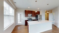 This single-floor residence at 2320 offers a thoughtfully designed open-concept layout that seamlessly connects the kitchen and living areas. The kitchen is a standout feature, showcasing rich dark-wood cabinetry extending to the ceiling, a subway tile backsplash, and a full suite of stainless steel appliances including a gas range, built-in microwave, and refrigerator. A large center island with a crisp white countertop and undermount sink provides generous prep space and serves as a natural gathering point. Pendant lighting above the island adds a refined touch. The open living and dining area benefits from multiple windows that invite abundant natural light and is finished with warm hardwood flooring throughout. A glass-paneled door in the kitchen provides additional access and light. The bedrooms are carpeted for comfort and feature neutral tones, natural window light, and walk-in closet space. The bathrooms are finished with large-format tile flooring and walls. One bathroom includes a soaking tub with tiled surround, while another features a frameless glass-enclosed walk-in shower with floor-to-ceiling linear tile, a built-in shelf, and a bench seat. The overall aesthetic is clean, modern, and move-in ready.