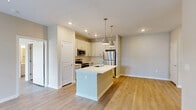 Located at 1090 Summersweet Drive in New Bern, NC, this well-appointed 2-bedroom, 2-bathroom residence offers a thoughtfully designed single-floor layout with a clean, contemporary aesthetic throughout. Light wood-style flooring flows consistently across the living spaces, complementing the neutral warm-toned walls and bright white trim.

The open-concept kitchen and living area serves as the heart of the home, featuring a central island with a light quartz countertop, undermount sink, and dishwasher, all highlighted by stylish pendant lighting overhead. White shaker cabinetry, a subway tile backsplash, and a full suite of stainless steel appliances complete the modern kitchen.

The spacious primary bedroom includes a ceiling fan, access to natural light, and a generously sized walk-in closet outfitted with multi-tier wire shelving. The primary bathroom offers a long vanity with quartz countertops, a glass-enclosed walk-in shower, and wood-look flooring. The second bathroom features a full tub-shower combination with clean white tile surround.

The second bedroom is bright and well-proportioned, with a ceiling fan and ample natural light. A set of French doors in the living area opens to an outdoor space, enhancing the home's connection to the exterior. A dedicated hallway connects all rooms, providing a logical and efficient flow throughout the residence.