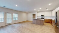 Located at 7325 Quivira Rd in Shawnee, KS, this two-bedroom, one-bathroom residence offers a thoughtfully designed single-floor layout with a clean, modern aesthetic throughout. The standout feature is the contemporary kitchen, which boasts two-tone cabinetry — warm wood lower cabinets paired with crisp white upper cabinets — complemented by white quartz countertops, a subway tile backsplash, a central island, and a full suite of stainless steel appliances. Light wood-style luxury vinyl flooring runs through the kitchen, living area, and primary bedroom, adding warmth and continuity across the main living spaces. The two bedrooms are well-proportioned, with the primary bedroom featuring a ceiling fan and a sliding double-door closet, while the second bedroom offers plush carpeting, a ceiling fan, and a window with outdoor views. The full bathroom is efficiently laid out with warm wood vanity cabinetry, white countertops, a tub-shower combination, and matching luxury vinyl flooring. The entryway provides a welcoming transition into the living spaces, with clean white walls, recessed lighting, and multiple doorways connecting each room in a practical, open flow.
