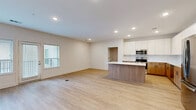 Located at 7325 Quivira Rd in Shawnee, KS, this two-bedroom, one-bathroom residence offers a thoughtfully designed single-floor layout with a clean, modern aesthetic throughout. The standout feature is the contemporary kitchen, which boasts two-tone cabinetry — warm wood lower cabinets paired with crisp white upper cabinets — complemented by white quartz countertops, a subway tile backsplash, a central island, and a full suite of stainless steel appliances. Light wood-style luxury vinyl flooring runs through the kitchen, living area, and primary bedroom, adding warmth and continuity across the main living spaces. The two bedrooms are well-proportioned, with the primary bedroom featuring a ceiling fan and a sliding double-door closet, while the second bedroom offers plush carpeting, a ceiling fan, and a window with outdoor views. The full bathroom is efficiently laid out with warm wood vanity cabinetry, white countertops, a tub-shower combination, and matching luxury vinyl flooring. The entryway provides a welcoming transition into the living spaces, with clean white walls, recessed lighting, and multiple doorways connecting each room in a practical, open flow.