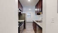 Located at 1880 E Shore Dr in Maplewood, MN, this one-bedroom, one-bathroom unit offers a well-designed, efficiently laid-out single-floor living space. The kitchen is a standout feature, showcasing rich dark cabinetry, granite-look countertops, stainless steel appliances including a refrigerator, range, and dishwasher, and a stainless steel sink — all set over durable light wood-look flooring. The galley-style kitchen flows seamlessly into the rest of the unit via connecting hallways.

The living room is bright and open, featuring the same wood-look flooring, a large sliding glass door that invites natural light and provides access to an outdoor space, and an additional window for added ventilation and views. Baseboard heating units are present throughout the unit for consistent comfort.

The spacious bedroom offers plush carpeting, a ceiling fan with light fixture, a dedicated window for natural light, and a generously sized walk-in style closet with built-in shelving and hanging rods — providing ample storage. The bathroom is clean and straightforward, featuring a full tub-shower combination with white tile surround and chrome fixtures. Two hallways connect the living areas and provide additional functional flow throughout the space.