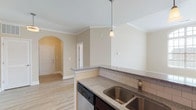 This single-floor residence on Warrick Trail offers a thoughtfully designed layout that balances functionality with comfort. The open-concept living and dining area is finished with warm hardwood-style flooring, crown molding, and large windows that allow natural light to pour in throughout the day.

The kitchen is a standout feature, equipped with dark espresso cabinetry, granite countertops, a subway tile backsplash, stainless steel appliances including a refrigerator, range, microwave, and dishwasher, and a double basin undermount sink. A peninsula with pendant lighting separates the kitchen from the living area, creating a natural flow between spaces. Track lighting above the kitchen adds additional illumination.

The bedrooms are carpeted for comfort and each features a ceiling fan with light fixture and windows with blinds that invite natural light. Ample closet space is provided, including a double-door closet visible from the kitchen corridor.

Two full bathrooms are finished consistently with granite-topped vanities, dark cabinetry, and tub-shower combinations. The arched entryway near the front door adds a classic architectural touch, while crown molding throughout the main living areas contributes to a refined, cohesive aesthetic. The overall palette of warm neutral tones creates a bright and welcoming atmosphere.
