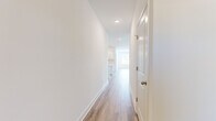 This thoughtfully designed single-story home offers a clean, modern aesthetic throughout, with a consistent palette of crisp white walls and light wood-tone flooring that creates a bright and cohesive feel. The open-concept living area is generously proportioned, bathed in natural light from multiple windows, and finished with a ceiling fan overhead — lending a comfortable, airy ambiance. The kitchen is a standout feature, showcasing white shaker-style cabinetry, a classic subway tile backsplash, quartz countertops, and a large center island. Stainless steel appliances complete the space, making it as functional as it is visually appealing. Two well-lit hallways connect the home's rooms with ease. The three bedrooms are finished with plush carpet flooring and feature windows that bring in natural light and outdoor views. The generously sized primary bedroom is accompanied by a walk-in closet with wire shelving and hanging rods for ample storage. Both bathrooms are finished with wood-look flooring and brass-toned fixtures; one includes a full soaking tub and shower combo. A dedicated laundry room with utility hookups adds everyday convenience. The attached garage provides additional storage and parking, completing this practical and stylish home.