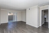 Located at 55 Pharr Rd NW in Atlanta's prestigious Buckhead neighborhood, this single-floor residence offers a thoughtfully designed layout with consistent, modern finishes throughout. Dark hardwood-style flooring runs through the main living areas, complemented by neutral-toned walls and clean white baseboards and crown molding that add a polished, cohesive feel.

The spacious living area is a standout, featuring crown molding, abundant natural light, and a full-length sliding glass door with vertical blinds that opens to an outdoor patio, creating a seamless indoor-outdoor connection. The kitchen is well-equipped with stainless steel appliances, including an electric range and refrigerator, granite-style countertops, white cabinetry, and a subway tile backsplash — all set atop matching dark hardwood-style flooring.

The bedroom offers plush carpeting, a ceiling light fixture, a closet, and a window with blinds that allows for natural light and outdoor views. The bathroom is neatly finished with white beadboard wainscoting, a vanity with granite-style countertops, a framed mirror with vanity lighting, brushed nickel fixtures, and coordinating hardwood-style flooring. A dedicated hallway connects the rooms efficiently, with visible closet space and easy access to all areas of the unit.
