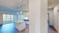 This single-story, 4-bedroom, 2-bathroom residence offers a clean, modern design with consistent wood-look flooring and a neutral color palette throughout. The open-concept kitchen serves as a central hub, featuring a center island with a light countertop, crisp white cabinetry, stylish brass pendant lighting, and stainless steel appliances. Large windows fitted with white horizontal blinds allow generous natural light to flow into the living areas and bedrooms, creating a bright and airy ambiance.

The four bedrooms are well-proportioned and bright, each finished with the same durable wood-look flooring and neutral walls. Several rooms feature ceiling fans and multiple windows, offering good ventilation and natural views to the outdoors. The primary bedroom provides a comfortable amount of space for a full furniture arrangement.

Both bathrooms are finished to a consistent modern standard. One bathroom features a full soaking tub with large-format white tile surround and a built-in niche, complemented by brushed nickel fixtures. The second bathroom includes a white undermount sink, white cabinetry, and a contemporary rounded mirror with modern vanity lighting.

Additional highlights include two closets for storage, and a dedicated laundry room equipped with a full-size washer and dryer and overhead wire shelving. The layout is connected by multiple hallways, providing clear circulation throughout the home.