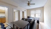 This efficient one-bedroom, one-bathroom unit is thoughtfully laid out across a single floor, making smart use of every square foot. The primary room is generously proportioned relative to the overall footprint, offering ample space for sleeping, living, and dining areas all in one open arrangement. Hardwood floors run throughout the main living area, lending warmth and character, while a ceiling fan with a light fixture provides both comfort and ambient lighting. A window allows natural light to fill the room, creating a bright and inviting atmosphere.

The kitchen is compact yet fully functional, featuring warm oak cabinetry, granite-style countertops, a stainless steel sink, and a white gas range — providing everything needed for everyday cooking. A hallway connects the main living area to the supporting rooms, maintaining a logical flow through the unit.

The bathroom offers a full soaking tub framed by marble-patterned tile walls and includes a frosted window for natural ventilation and privacy. A dedicated laundry area adds everyday convenience. A built-in closet in the primary room provides essential storage. Overall, this unit delivers a practical and self-contained living environment with classic finishes and functional design throughout.