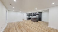 Located at 3140 State Route 209 in Kingston, NY, this thoughtfully designed 2-bedroom, 3-bathroom single-story home offers a clean, modern aesthetic throughout. Light hardwood flooring flows seamlessly across the entire residence, lending warmth and continuity to every room.

The open-concept kitchen and living area serves as the heart of the home, featuring dark gray shaker-style cabinetry, white quartz countertops with subtle veining, a white subway tile backsplash, and a full suite of stainless steel appliances. A central island provides additional prep and seating space, while large sliding glass doors flood the living area with natural light and open to lush, green outdoor surroundings.

Both bedrooms are bright and airy, with large windows framing natural greenery views. The primary bedroom offers a comfortable footprint with recessed lighting, and the second bedroom includes a double-door closet for generous storage. Clean white walls throughout create a fresh, minimalist backdrop.

The three bathrooms are finished with a consistent modern palette, featuring matte black hardware accents, white fixtures, wood-toned vanities, and dark tile flooring. Connecting hallways are clean and well-lit, maintaining the home's cohesive, contemporary feel. Set amid mature trees, this home combines modern finishes with a serene natural setting.
