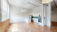 Located at 3700 Orleans Ave in New Orleans, this single-floor loft-style unit blends historic character with modern finishes. The open living area is defined by soaring ceilings, warm hardwood floors, and striking exposed brick walls that stretch across the main space. A graceful arched window frames natural light beautifully, while modern ceiling fans and pendant lighting complement the industrial-chic aesthetic with track lighting overhead.

The kitchen is thoughtfully designed with white shaker cabinetry extending to the ceiling, a teal subway tile backsplash, white countertops, and a full suite of stainless steel appliances including a French door refrigerator, range, microwave, and dishwasher. A peninsula provides additional prep space and a casual dining option.

The bathroom is clean and contemporary, featuring a sliding glass-enclosed walk-in shower with white tile, a sleek vanity with white countertop, and hardwood-style flooring. A dedicated laundry room with full-size washer and dryer adds everyday convenience.

Throughout the space, the contrast of raw brick, polished hardwood, and crisp white walls creates a distinctive New Orleans loft atmosphere that is both functional and full of character.