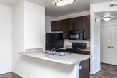 Located at 4422 S 120 W in Murray, Utah, this single-floor unit offers a well-organized layout designed for comfortable everyday living. The open-concept living and dining area is finished with rich, dark wood-style hardwood flooring that reflects natural light streaming in through multiple large windows fitted with horizontal blinds. A sliding glass door provides direct outdoor access, enhancing the sense of openness throughout the main living space.

The kitchen is positioned adjacent to the living area and features a peninsula-style breakfast bar with a built-in sink, offering both additional prep space and a casual dining option. Dark espresso cabinetry lines the kitchen walls, complemented by black appliances including a refrigerator, range, and microwave. The layout creates a seamless connection between cooking and living spaces.

The bedrooms are carpeted in neutral tones, providing a softer, quieter environment. Each room benefits from natural light through windows with blinds, and at least one bedroom includes a closet with built-in shelving. The bathroom is finished with stone-look tile flooring, a dark vanity with a wide countertop and integrated sink, a large mirror, and a full tub and shower combination. The unit's neutral color palette and consistent finishes create a clean, cohesive aesthetic throughout.