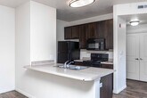 Located at 4422 S 120 W in Murray, Utah, this single-floor unit offers a well-organized layout designed for comfortable everyday living. The open-concept living and dining area is finished with rich, dark wood-style hardwood flooring that reflects natural light streaming in through multiple large windows fitted with horizontal blinds. A sliding glass door provides direct outdoor access, enhancing the sense of openness throughout the main living space.

The kitchen is positioned adjacent to the living area and features a peninsula-style breakfast bar with a built-in sink, offering both additional prep space and a casual dining option. Dark espresso cabinetry lines the kitchen walls, complemented by black appliances including a refrigerator, range, and microwave. The layout creates a seamless connection between cooking and living spaces.

The bedrooms are carpeted in neutral tones, providing a softer, quieter environment. Each room benefits from natural light through windows with blinds, and at least one bedroom includes a closet with built-in shelving. The bathroom is finished with stone-look tile flooring, a dark vanity with a wide countertop and integrated sink, a large mirror, and a full tub and shower combination. The unit's neutral color palette and consistent finishes create a clean, cohesive aesthetic throughout.